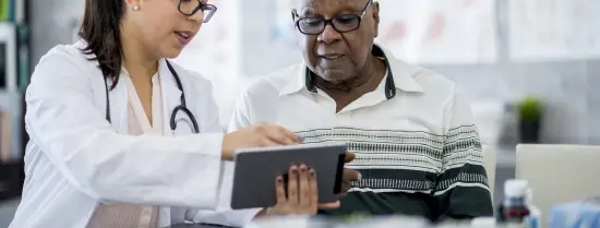 Zorgverlener helpt oudere man met een tablet