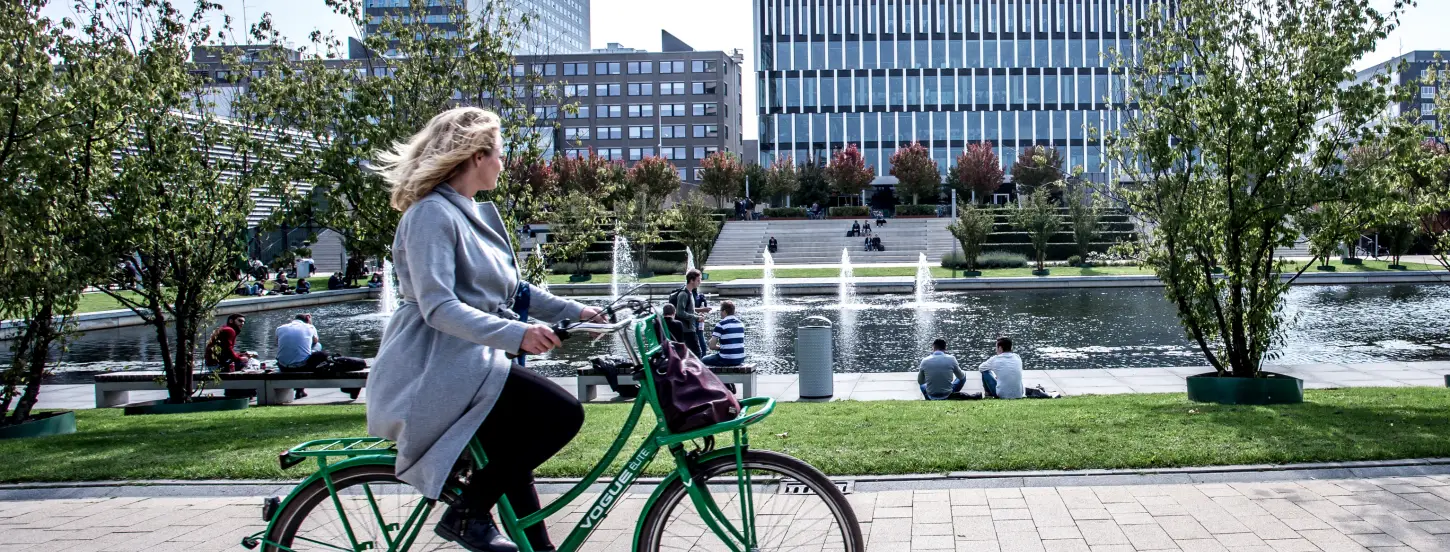 Person riding a bicycle on the campus Woudestein near the pond