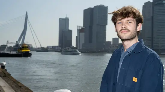 Arthur de Jaeger met op de achtergrond de Erasmusbrug en de hoogbouw van Rotterdam