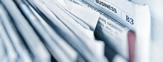 a row of newspapers with a bokeh effect with the focus on the business page 