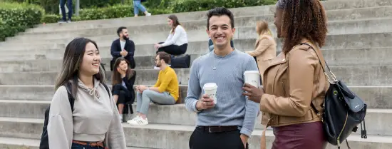 Students chatting on campus with a cup of coffee