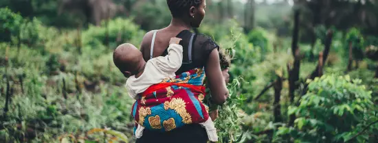 Person walking with a baby wrapped in a quilt on the back