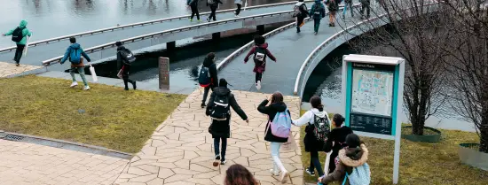 Studenten lopen over de brug op de campus.