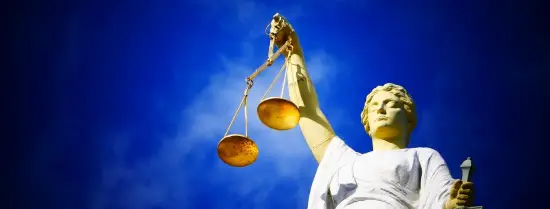 Vrouwe Justitia met weegschaal in hand met blauwe lucht als achtergrond