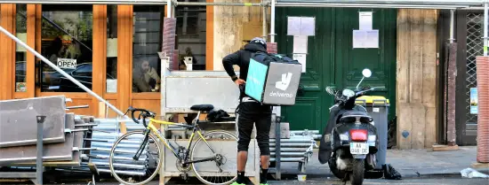 Man who works for Deliveroo is getting ready to hop on his bike.