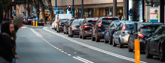 Een lange rij auto's staat in Rotterdam voor een rood stoplicht.