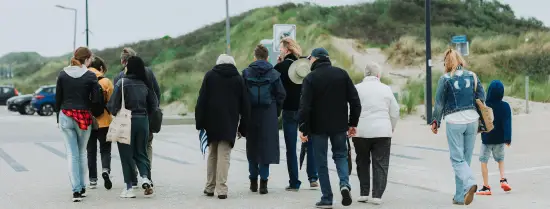 A group of people are walking to the beach at Hoek van Holland.