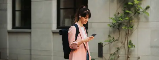 Student walks over street while looking at her phone.