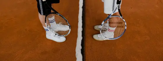 Twee sporters staan op de tennisbaan tegenover elkaar.